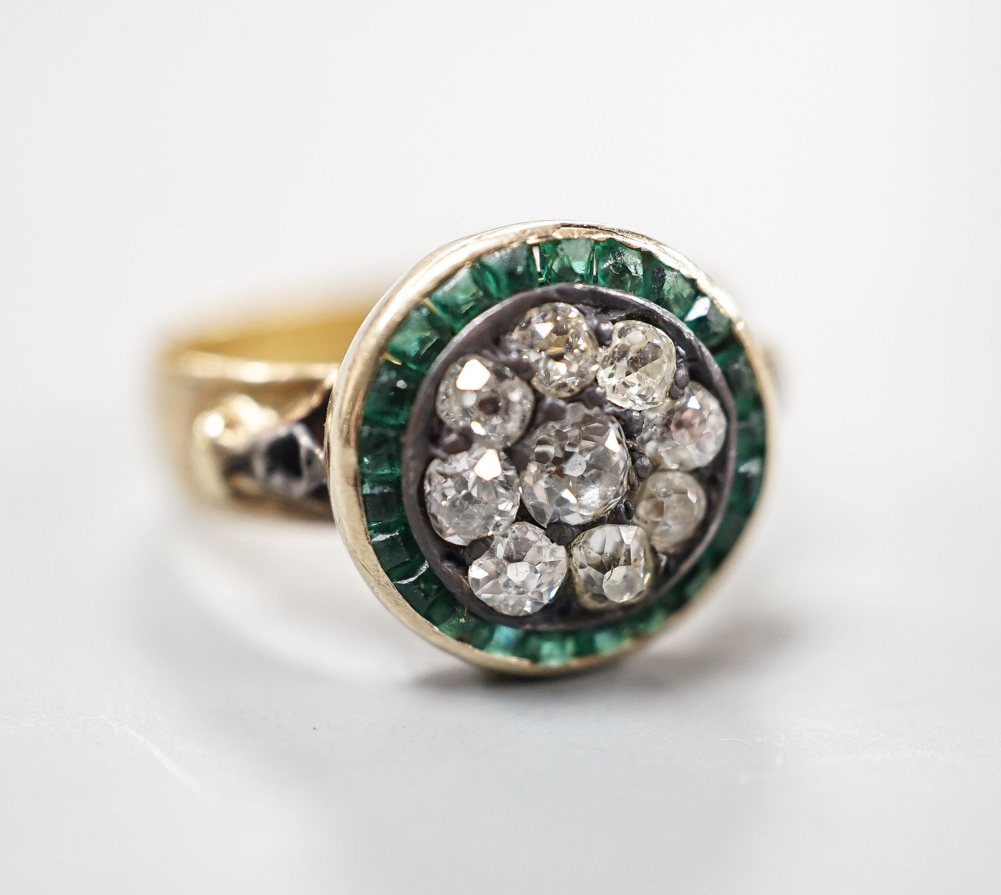 A George V 22ct gold emerald? and diamond set circular cluster ring, the shank with engraved inscription, size N/O, gross weight 5.3 grams.